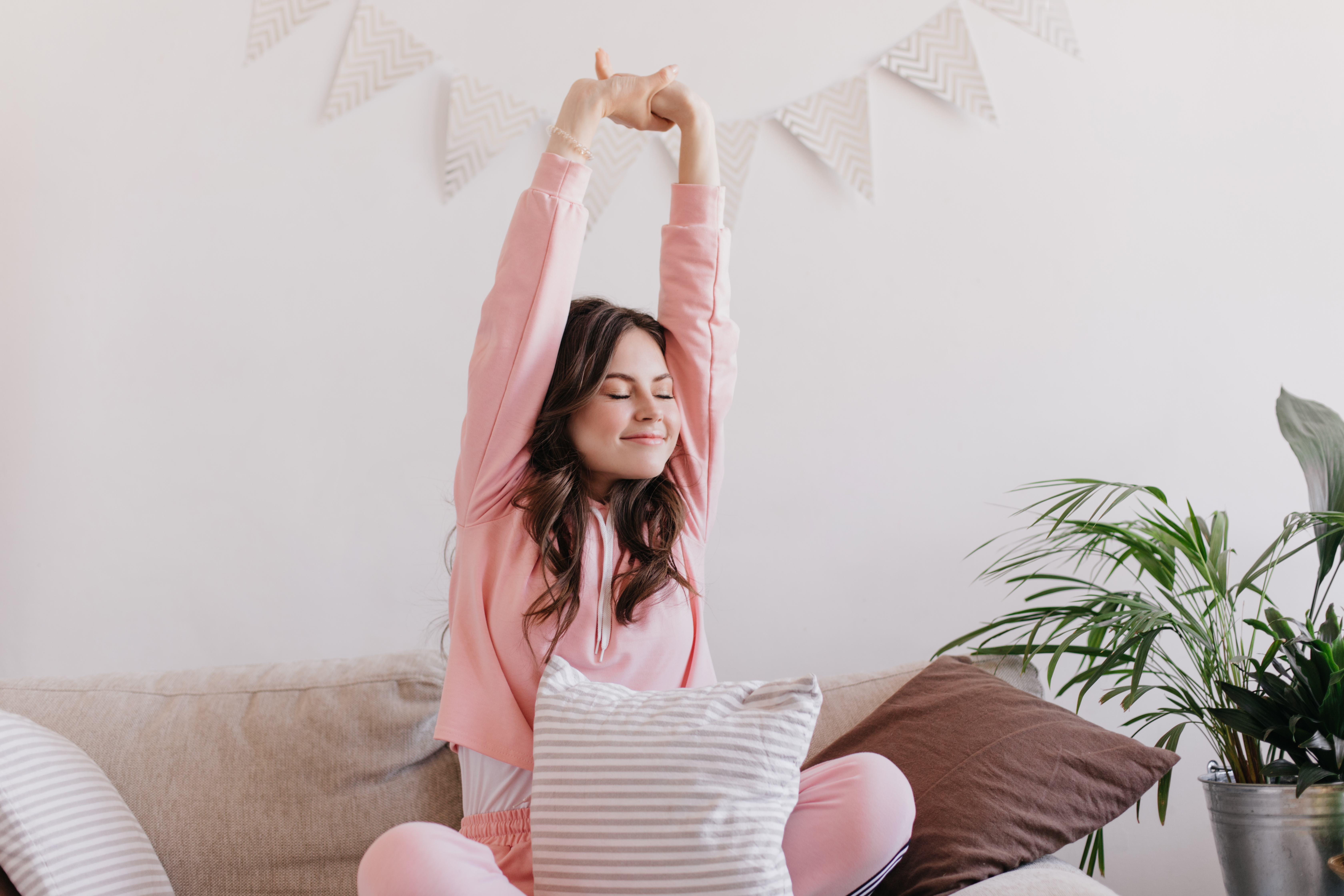Young woman happily stretching in the morning at home, representing a healthy morning routine and waking up energized